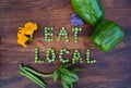 Ã¢â¬ÅEat LocalÃ¢â¬Â phrase made of green peas on wooden background